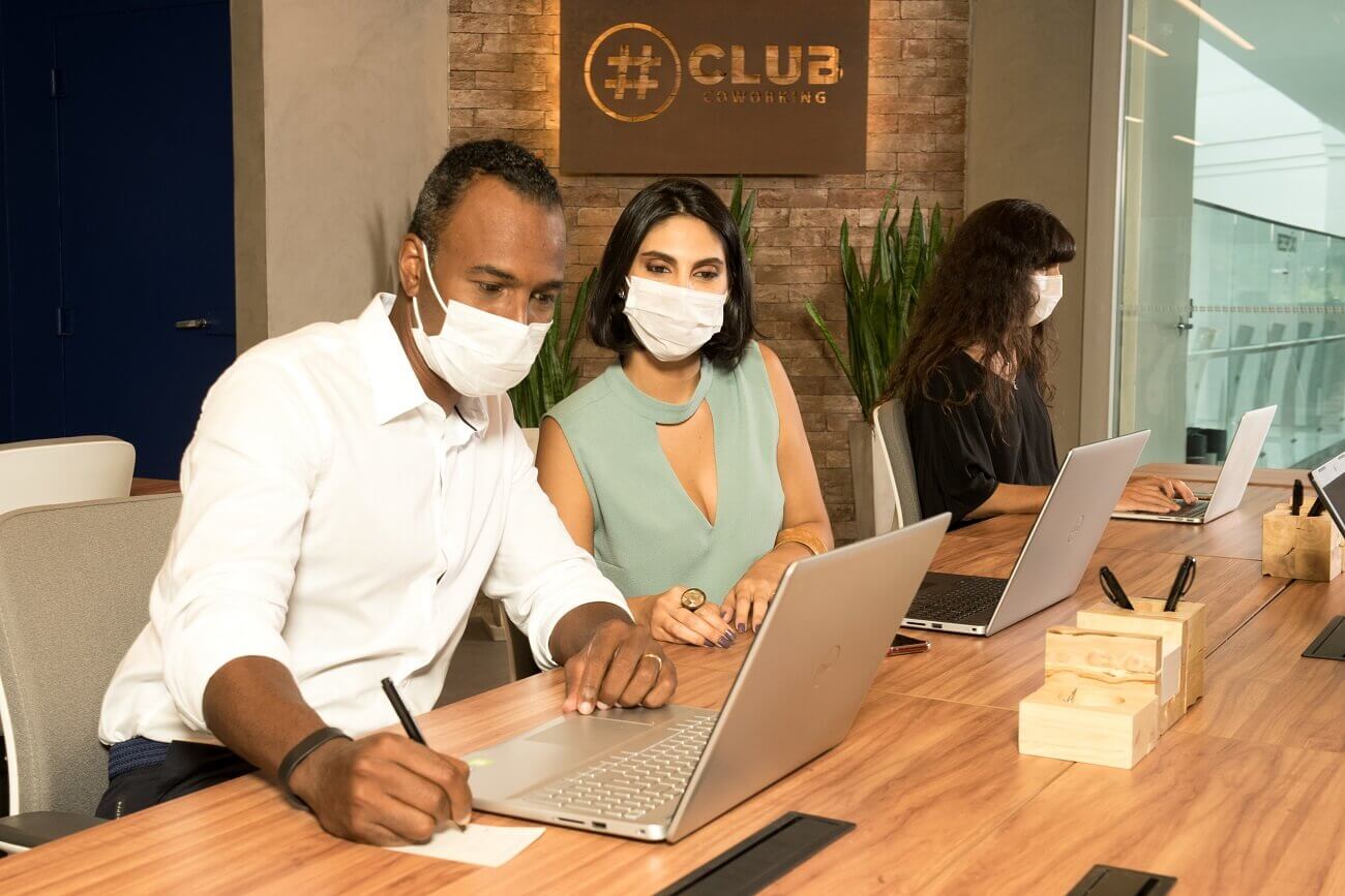 Equipe de homem e mulher trabalha em espaço coworking em modelo de trabalho híbrido