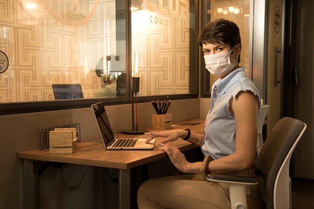 Mulher trabalhando em espaço coworking com estrutura e design que ajudam produtividade
